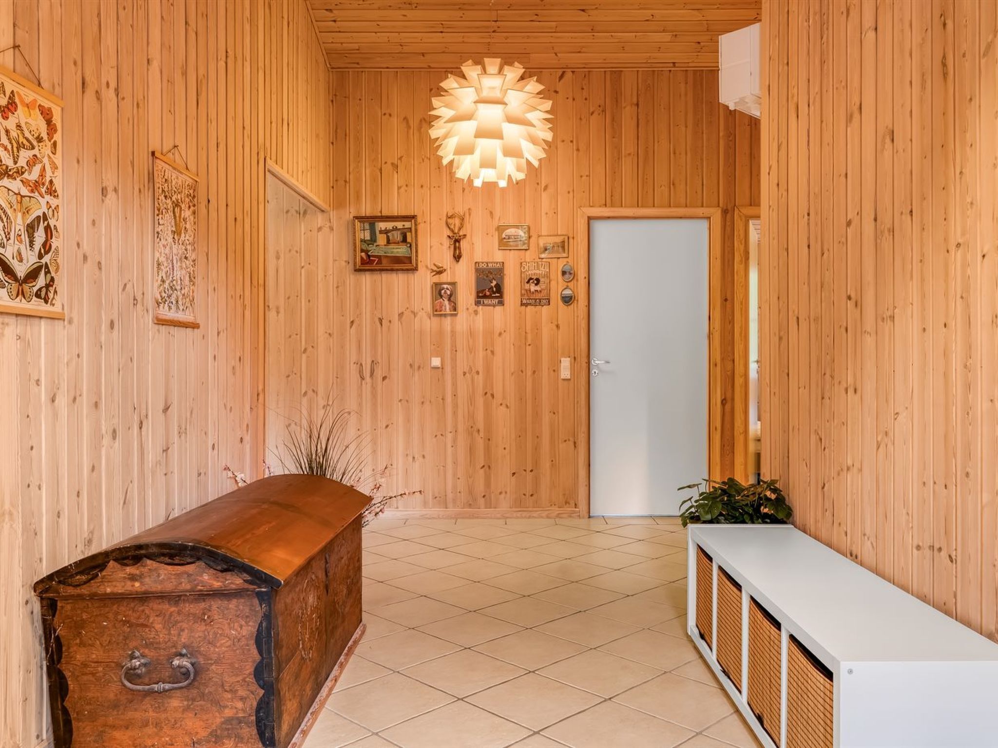 Un interior de madera con una mesa de recepción, un aplique de pared y cuadros enmarcados.