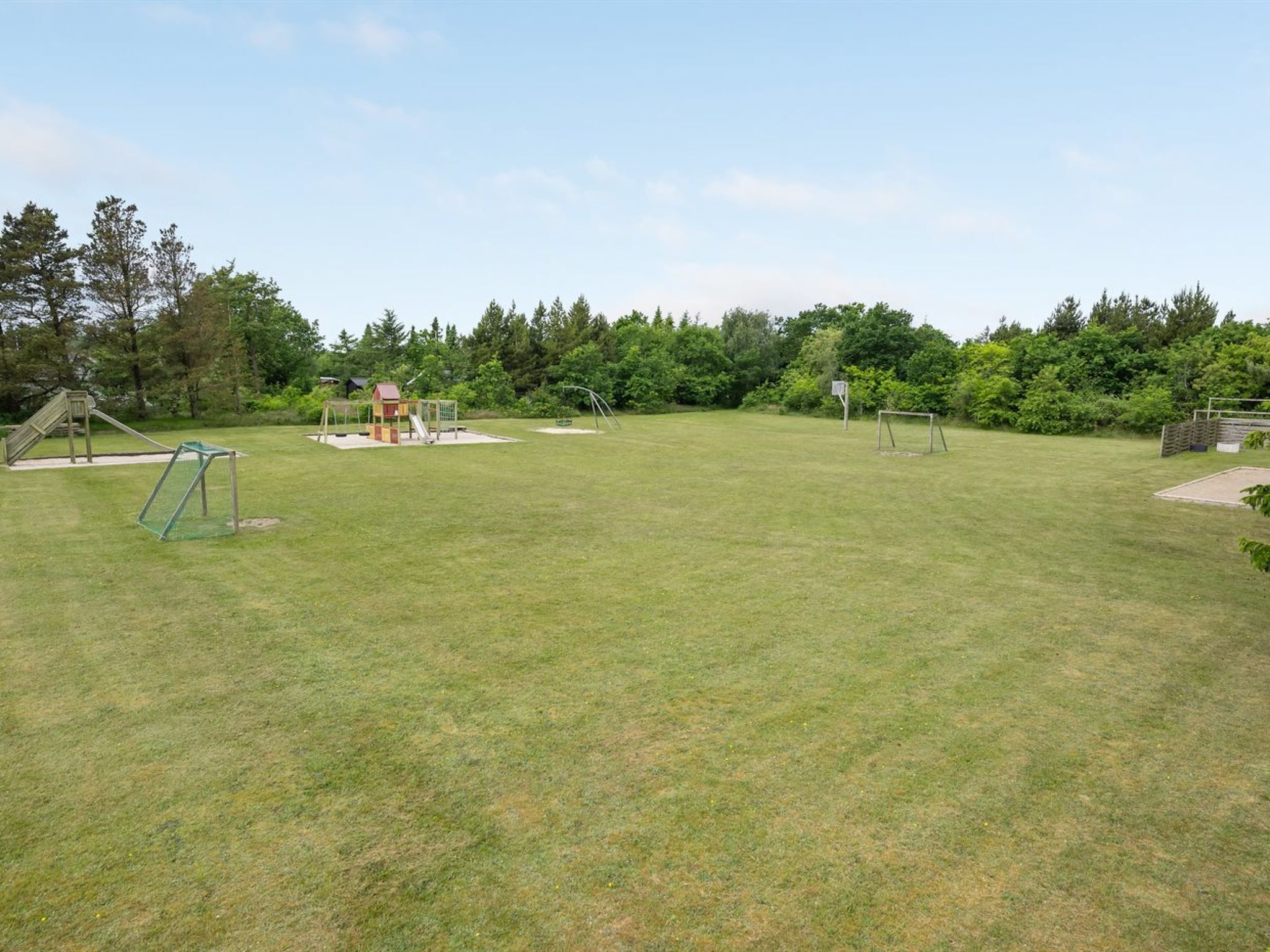 A grassy outdoor area with playground equipment including a slide and swings.