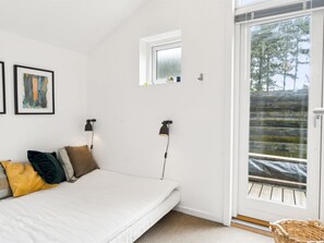 Une chambre à coucher avec un lit, une fenêtre et une porte donnant sur un balcon.