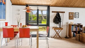 Ein moderner Essbereich mit Holzboden, einem Tisch mit roten Stühlen und Blick ins Freie.