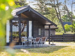Une cabane en bois dotée d’un patio couvert et de meubles d’extérieur.