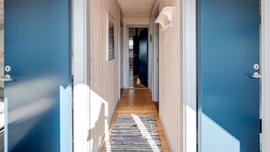 A hallway with blue doors, wooden flooring, and a hanging light fixture.