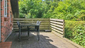 Eine Terrasse mit Tisch und Stühlen, eine Backsteinmauer und ein Holzzaun.