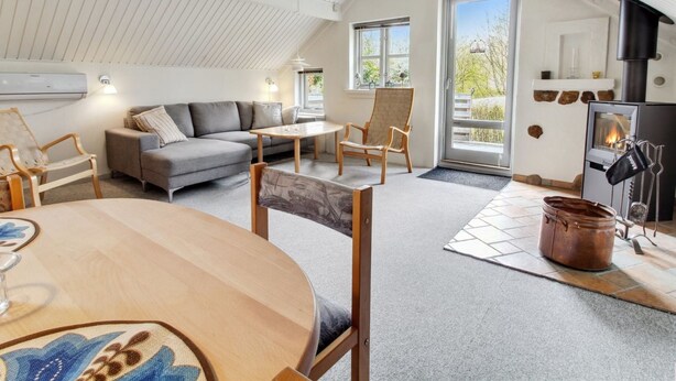 Ein gemütliches Wohnzimmer mit hoher Decke, einem Kamin und einem Essbereich mit Tisch und Stühlen.