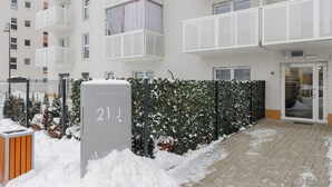 Un bâtiment moderne doté de balcons, une enseigne indiquant l’unité 21 et une entrée recouverte de neige.