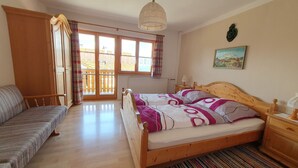 A bedroom with a wooden bed, a sofa, a window with a view, and a radiator. - Ferienhaus für 5 Personen, 2 Seperate Schlafzimmer (Anger)