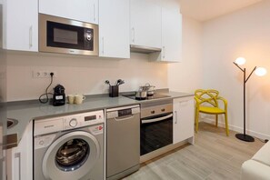 Una cocina compacta equipada con microondas, horno, lavavajillas y lavadora.