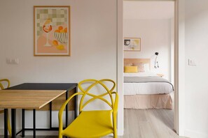 Una habitación con cama, mesita de noche, lámpara y un cuadro en la pared.