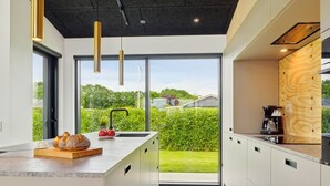 Cozinha moderna com uma ilha grande, pia e vista para o exterior.