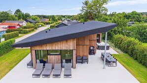 Uma casa moderna com um amplo terraço, mobiliário de exterior e uma banheira de hidromassagem.