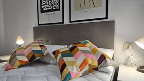 Un lit avec un oreiller à motifs, une tête de lit et deux œuvres d’art encadrées accrochées au mur.