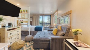 Une chambre à coucher de taille modeste, comprenant un lit, un canapé, un bureau et une fenêtre donnant sur la verdure.