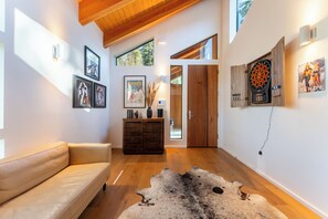 A modern interior with a leather sofa, a wooden cabinet, and a dartboard on the wall.