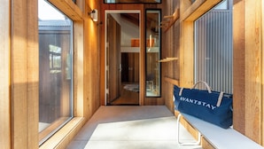 Un couloir intérieur en bois, doté de grandes fenêtres, d’un banc et d’un sac bleu sur lequel on peut lire le mot « AVANTSTAY ».