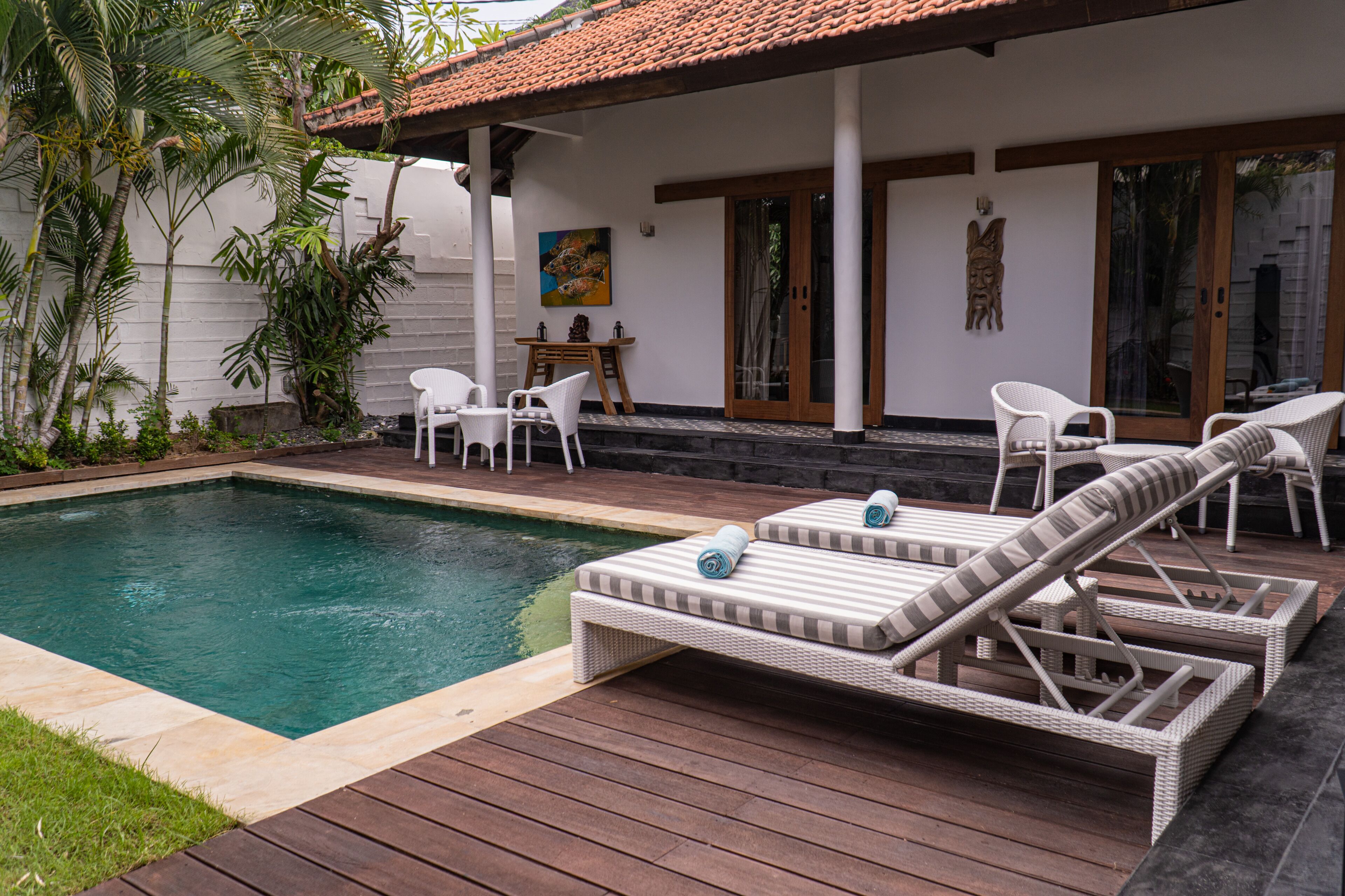 Un espace aménagé au bord de la piscine, avec des chaises longues, une table et des chaises.
