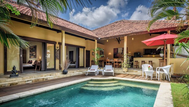 A swimming pool with lounge chairs, a dining area, and a kitchen. - Villa Inti Seminyak Bali (Seminyak)