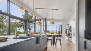 A modern kitchen with a large island, wooden flooring, and large windows offering a view of the outdoors. - "Rakita" - 75m from the sea by Interhome (Sjællands Odde)