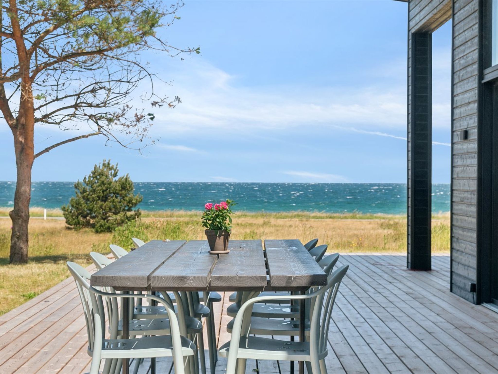 A wooden deck with a table and chairs, overlooking a body of water.