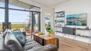 A modern living room with a leather sofa, a hanging chair, a wooden coffee table, and a fireplace. - "Rakita" - 75m from the sea by Interhome (Sjællands Odde)