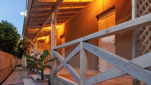 Un espace extérieur abrité, doté d’une terrasse en bois, de plantes en pot et d’une clôture à treillis.