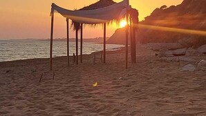 Una platja amb una construcció de palla i un ocre al fons.