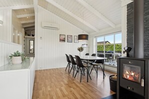 Una cocina moderna con comedor, paredes blancas, suelo de madera, estufa y un ventanal grande.