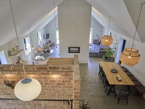 Relax in a spacious interior with a high ceiling, featuring a dining area and a living space with a sofa and television.