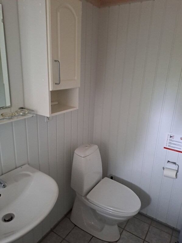 Un bagno con il water, un lavandino e un armadietto.
