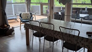 A dining area with a table and chairs, a view of the outdoors, and a ceiling with beams. - Cozy summer house and annex in tranquility (Glesborg)