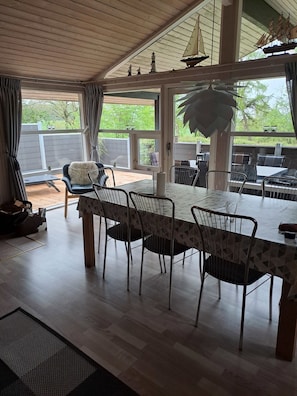 A dining area with a table and chairs, a view of the outdoors, and a ceiling with beams. - Cozy summer house and annex in tranquility (Glesborg)