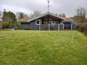 A house with a sloped roof, a fenced yard, a picnic table, and a bench. - Cozy summer house and annex in tranquility (Glesborg)