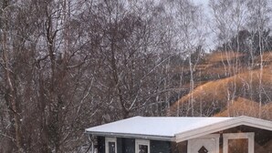 A small, dark-colored cabin with a white roof, a door, and two windows. - Cozy summer house and annex in tranquility (Glesborg)