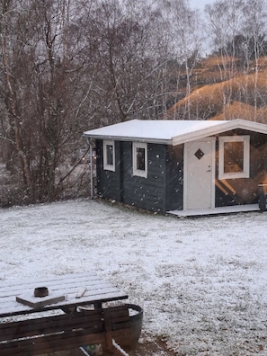 A small, dark-colored cabin with a white roof, a door, and two windows. - Cozy summer house and annex in tranquility (Glesborg)