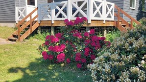 A house with a covered porch, a wooden staircase, and a garden with pink flowers. - Well-located holiday home in Ristinge, Langeland (Humble)