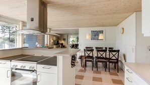 A modern kitchen with a large island, a built-in oven, and a dining area with chairs and a table. - Well-located holiday home in Ristinge, Langeland (Humble)