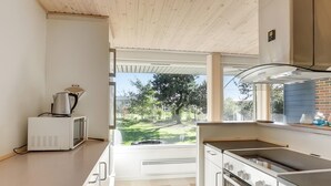 A kitchen with a microwave, stove, and a view of a garden. - Well-located holiday home in Ristinge, Langeland (Humble)
