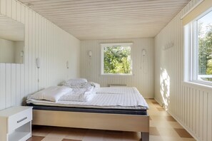 Un dormitorio con cama, mesita de noche, ventana y radiador.