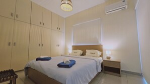 Una habitación de hotel con cama, mesita de noche, equipo de aire acondicionado y armario.