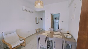 Un comedor con una mesa dispuesta para cuatro personas, un sofá y una lámpara colgante.