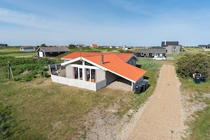 Une maison située sur la côte, avec une allée en gravier, un toit rouge et une façade blanche.