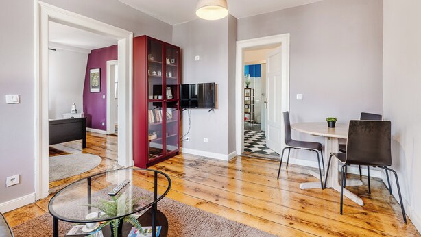 A modern living room with a glass coffee table, a red cabinet, and a dining area with a table and chairs. - Cozy apartment in the heart of Kulmbach (Kulmbach)