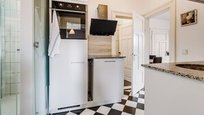 A modern kitchen with a black oven, white cabinets, and a checkered floor. - Cozy apartment in the heart of Kulmbach (Kulmbach)