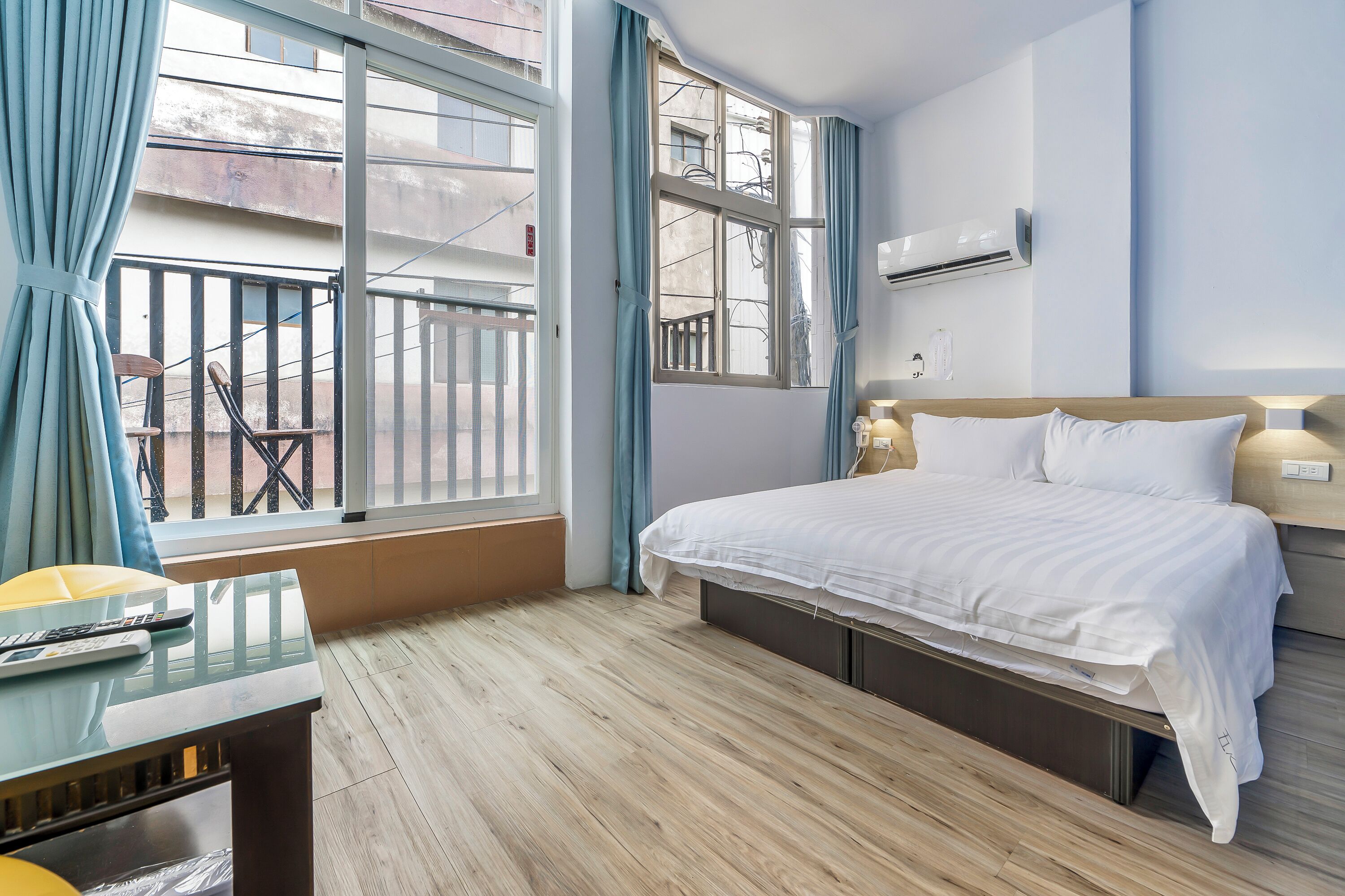 Une chambre d’hôtel avec un lit, un bureau, une chaise et une fenêtre avec des rideaux.