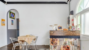 Un comedor con una mesa y sillas, un panel de madera decorativo y un ventanal con persianas.