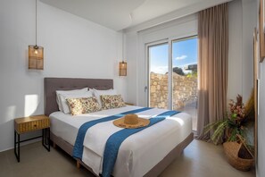 Ein Schlafzimmer mit einem Bett, Nachttischen, einem Fenster mit Vorhängen, Blick ins Freie und einer Pflanze.