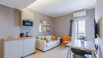Un espacio habitable compacto con kitchenette, un sofá, una mesa de comedor y una silla.
