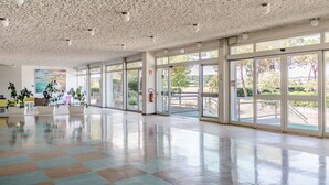 Eine großzügige Lobby mit hoher Decke, großen Fenstern und einem Schachbrettfußboden.