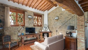 A rustic living room with a stone wall, wooden beams, a television, a fireplace, a sofa, and a wooden bench. - Wonderful private villa with A/C, WIFI, pool, TV, patio and pets allowed, close to Greve In Chia... (Castellina In Chianti)