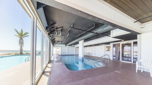 A pool area with clear views of the ocean, a palm tree, and a modern architectural ceiling with exposed pipes. - Royal Palms Condos (Gulf Shores)