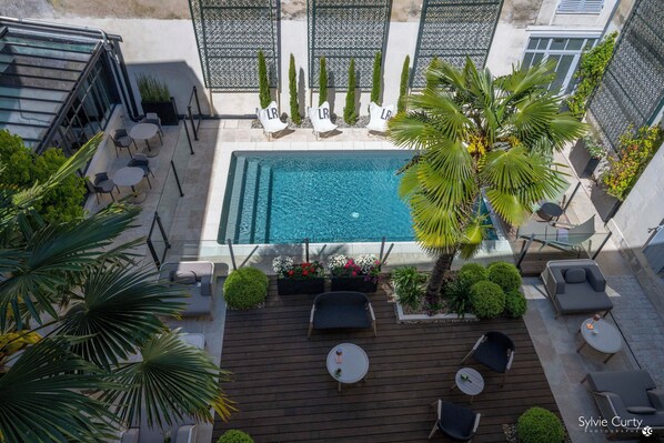 Relax by the pool surrounded by lush greenery and comfortable seating options.